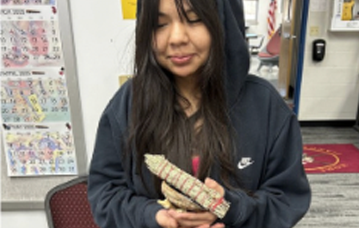 Student honored with clam shell, holder, bundle of sage and beaded lanyard