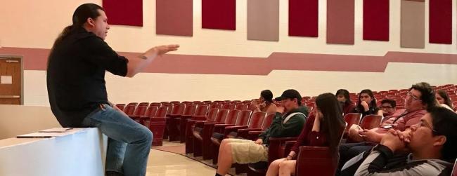 Instructor speaks to group of students in the school auditorium.